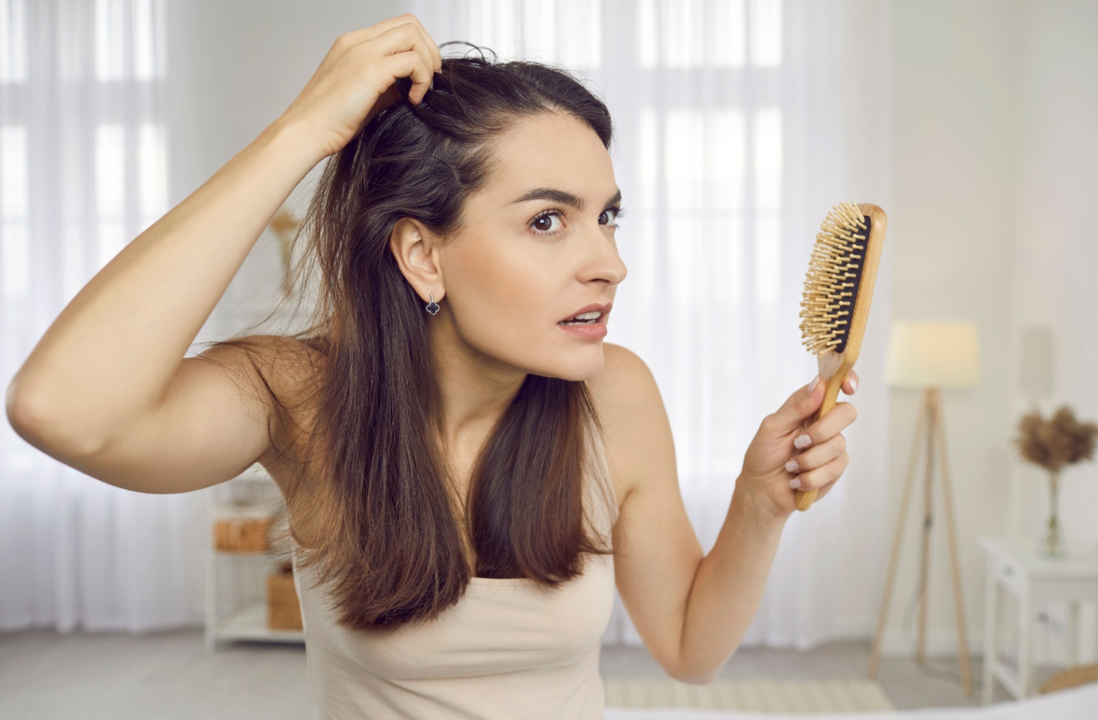 Person checking for hair thinning while holding a hairbrush.